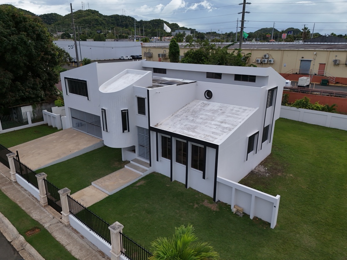 Low-angle drone shot of modern white residential property facade with manicured lawn in Hatillo, Puerto Rico