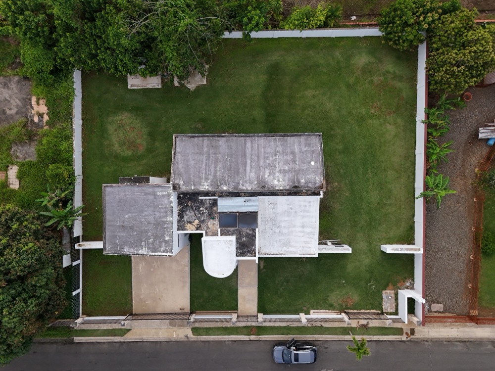 Straight-down aerial top view of residential property rooftop and surrounding green lawn in Hatillo, Puerto Rico